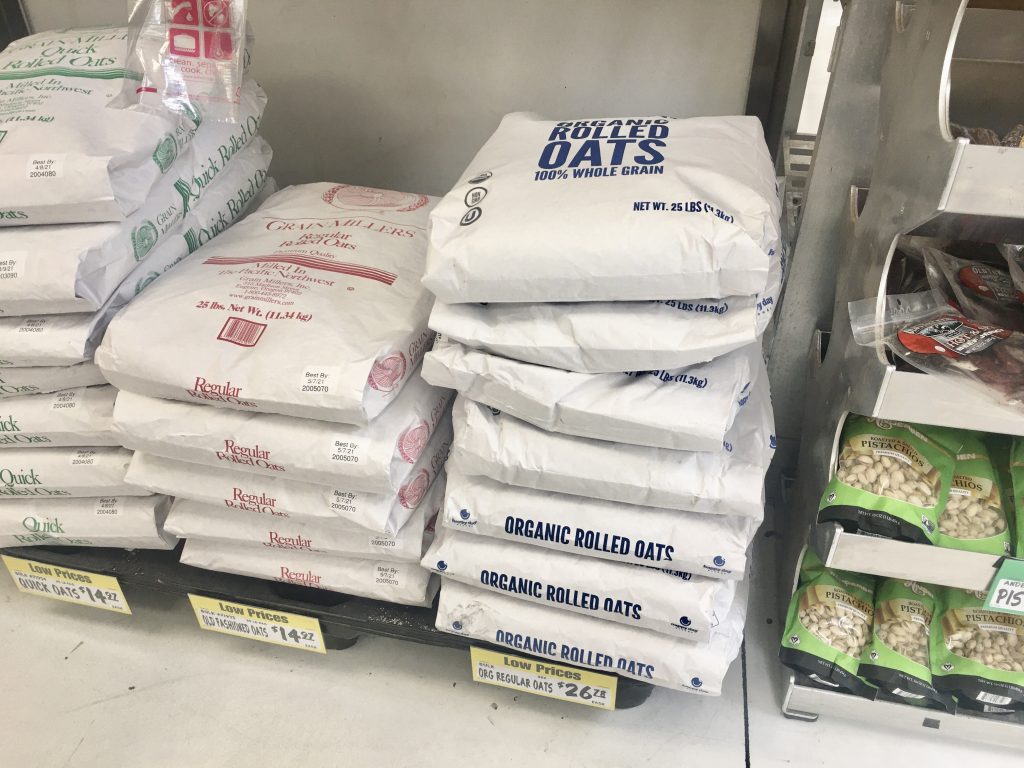 Winco foods bulk section showing price of 25 pound bag of organic rolled oats