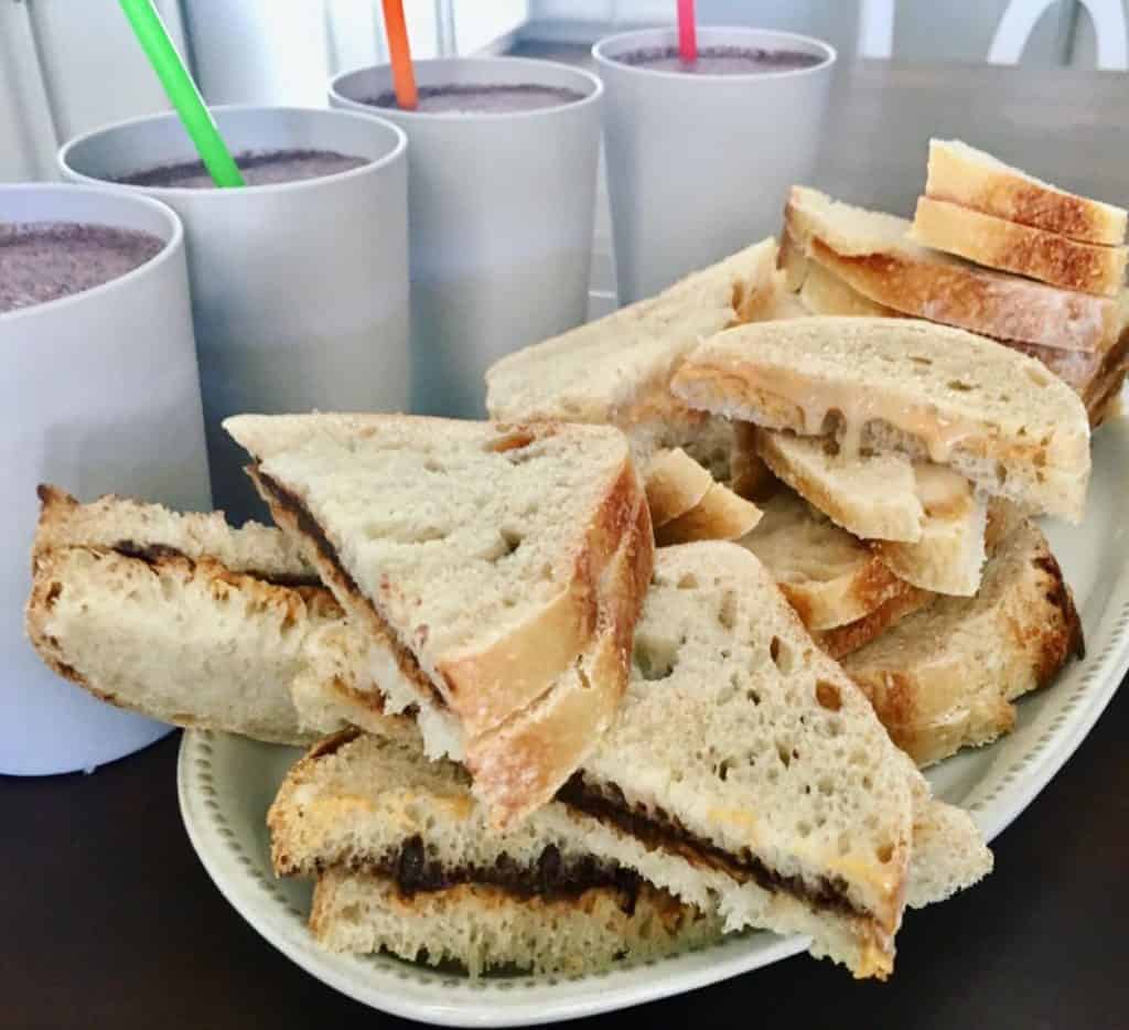 plate of sourdough bread sandwiches and smoothies on the side