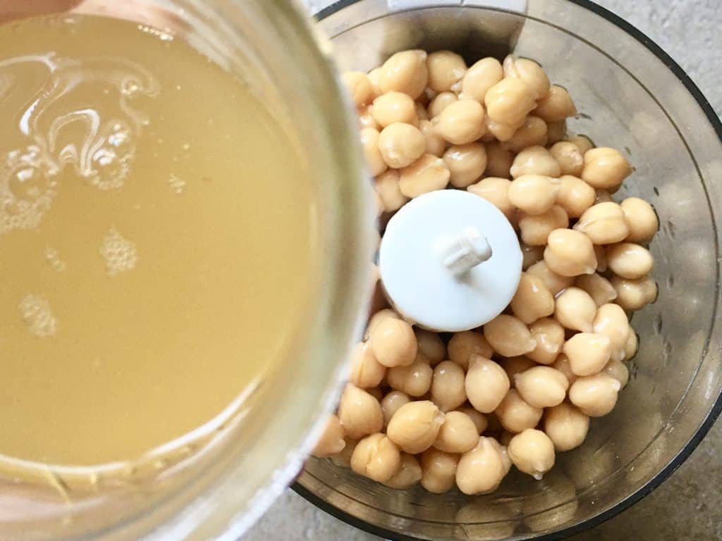 mini food processor filled with canned chickpeas and adding the aquafaba to the beans