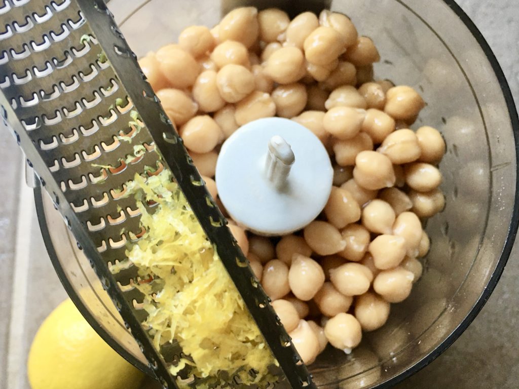 mini food processor with canned chickpeas and a microplane with lemon zest