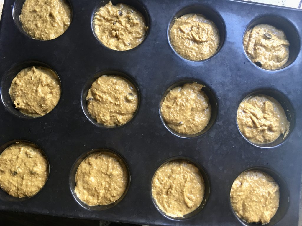 silicone muffin pan with pumpkin oatmeal muffin batter in each cup