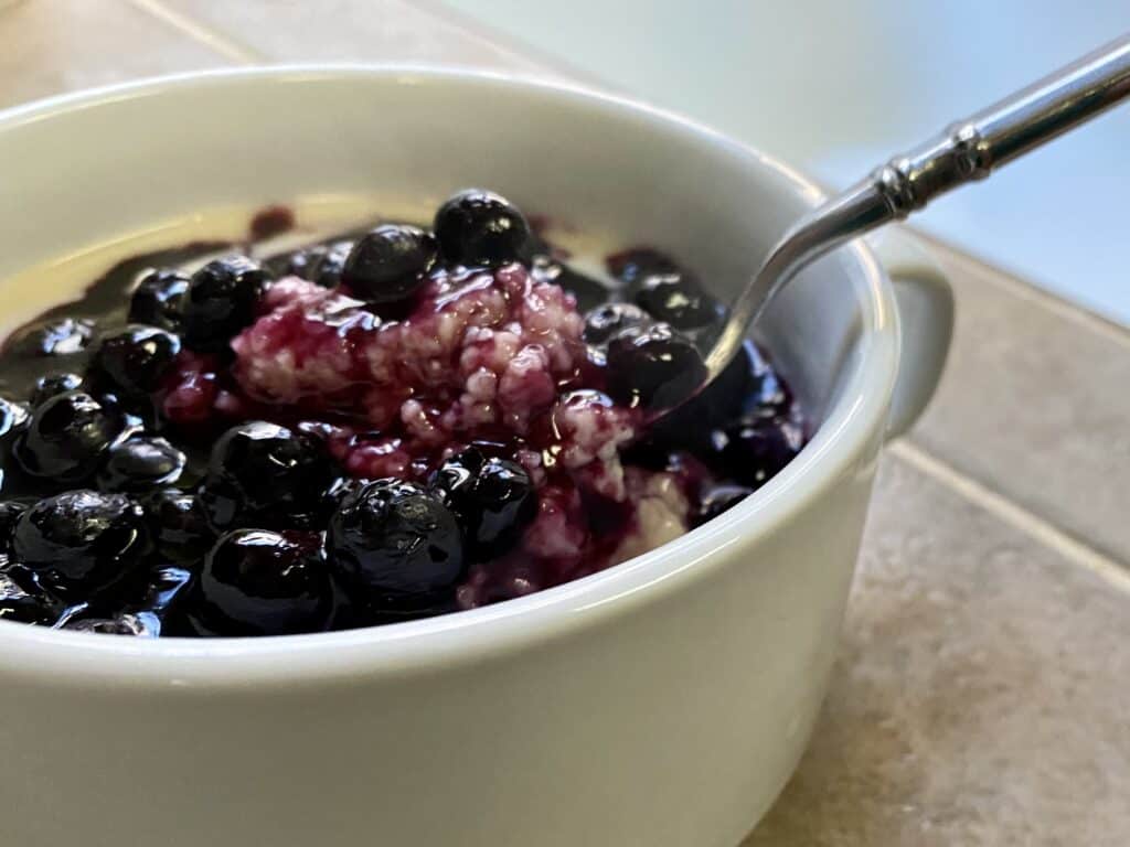 white bowl filled with cream of wheat and blueberry slurry