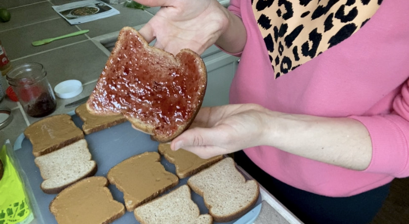holding up a piece of bread with jelly on it