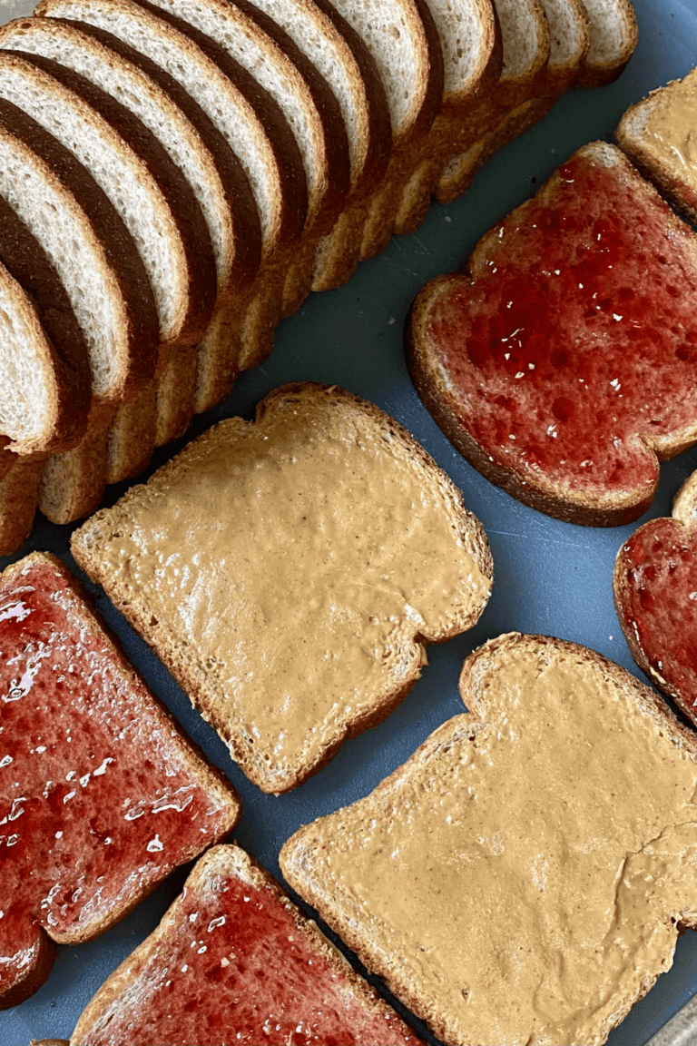 cutting board filled with pieces of bread making peanut butter and jelly