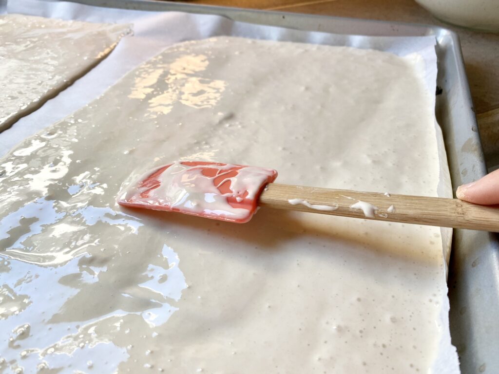 spread sourdough starter on parchment paper to make sourdough pizza crust