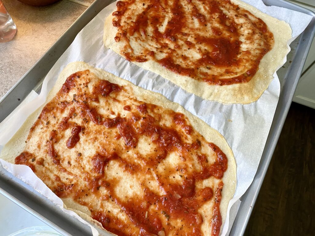 spread pizza sauce over sourdough pizza crust