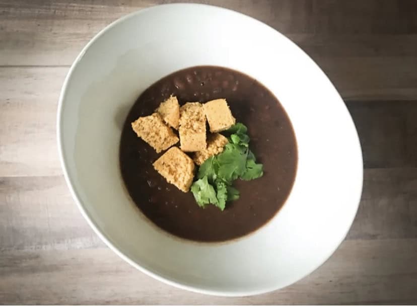 white bowl of black bean soup and cornbread muffins