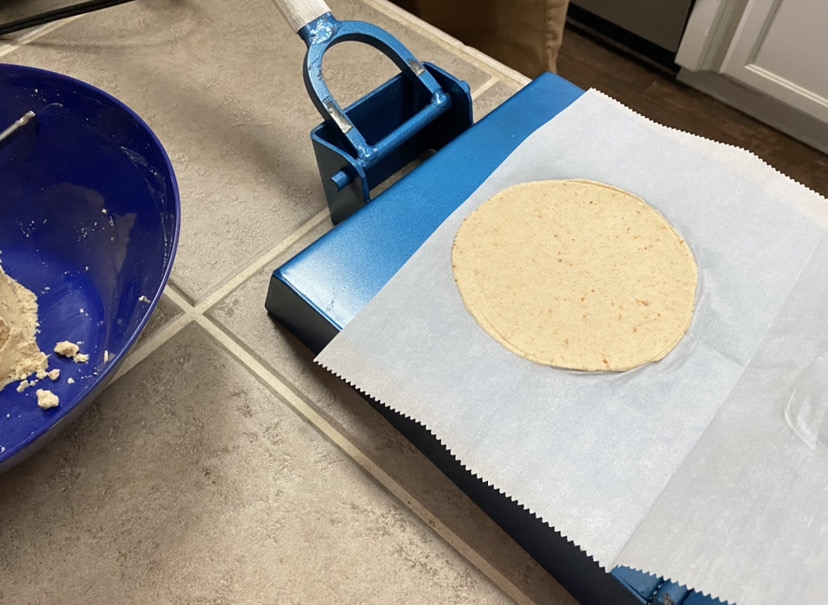 making corn tortillas with a large blue cast iron tortilla press