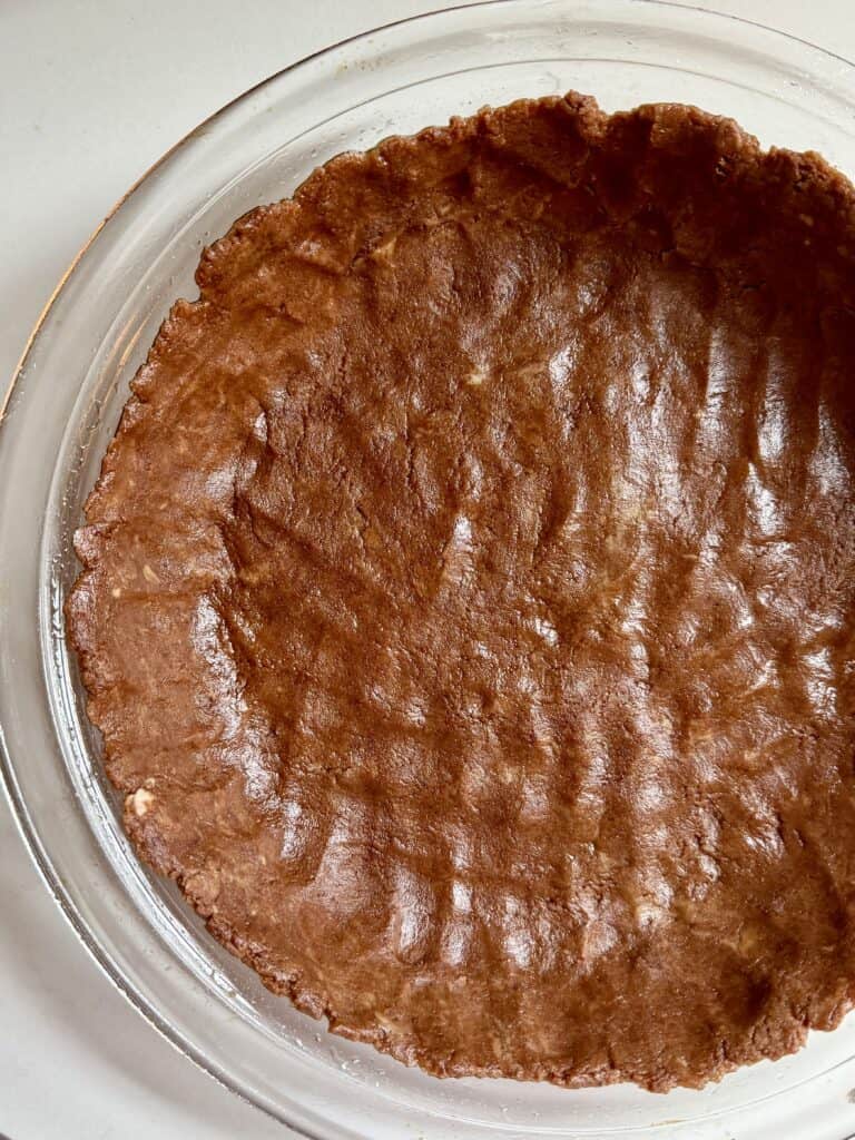 Aimee from Homemaker on a Budget presses chocolate crust into a pie plate.