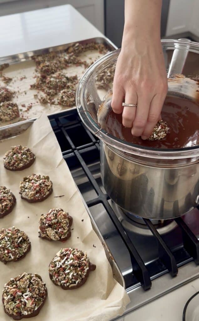 Aimee from Homemaker on a Budget dips nut clusters in chocolate.