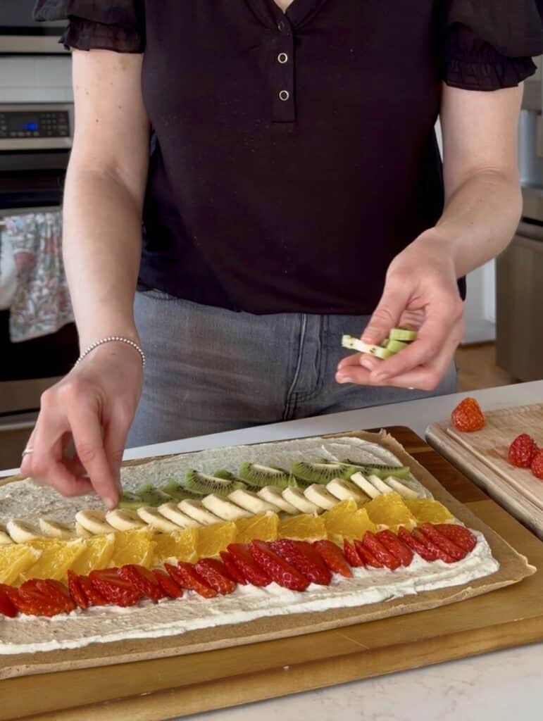 Aimee from Homemaker on a Budget arranges fruit on healthy fruit pizza. 