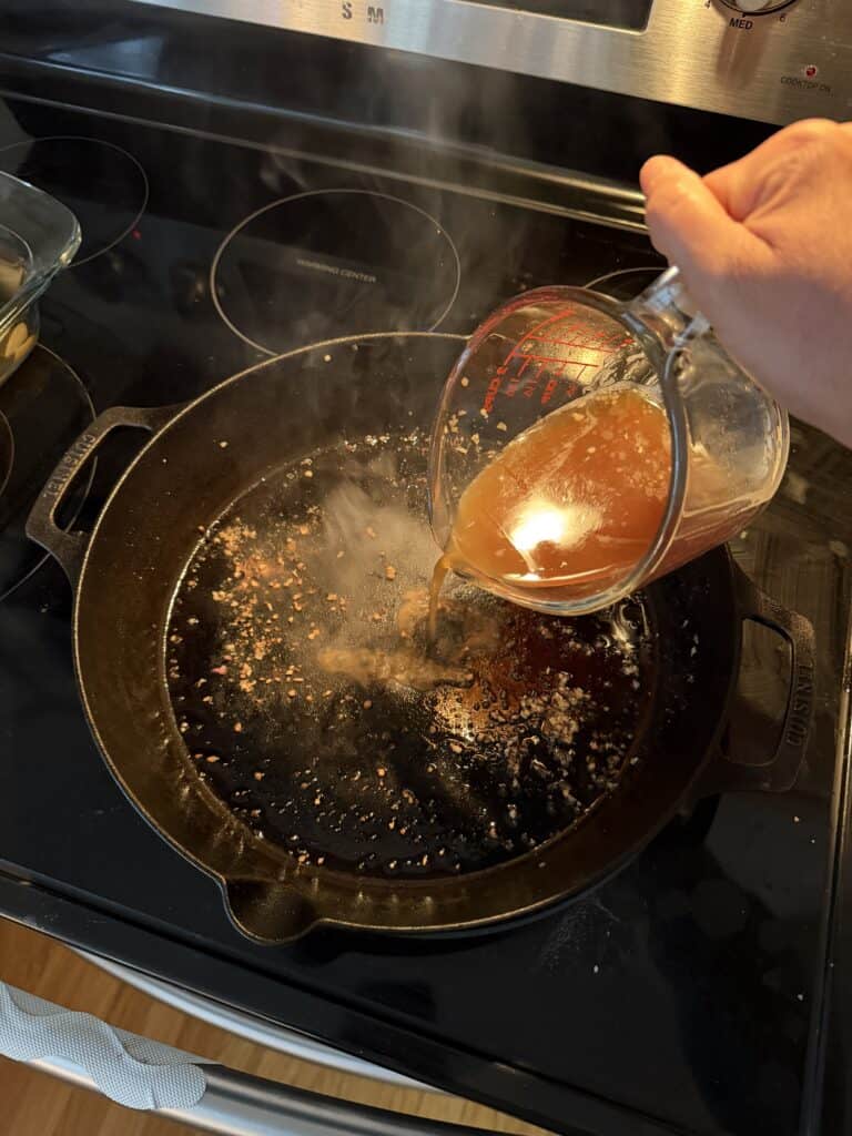 Aimee from Homemaker on a Budget deglazes a skillet to make broth for baked grass-fed beef chuck roast dish. 