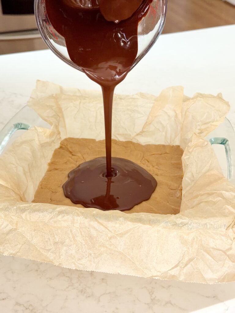 Aimee from Homemaker on a Budget layers chocolate and peanut butter in healthy no-bake buckeye bar recipe.