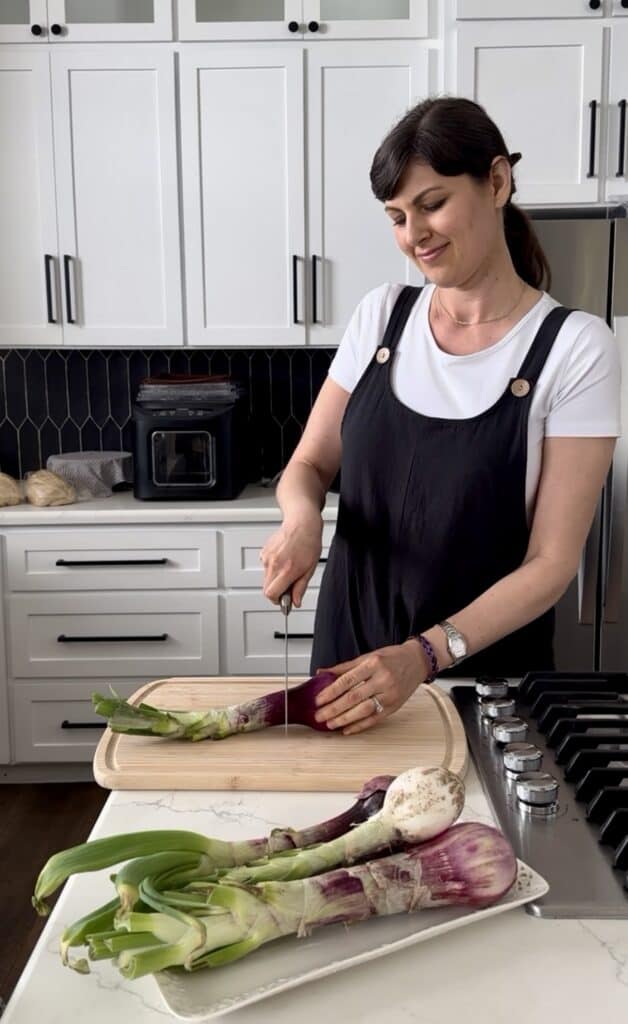 Aimee from Homemaker on a Budget slices red onions for a marinated onion recipe.