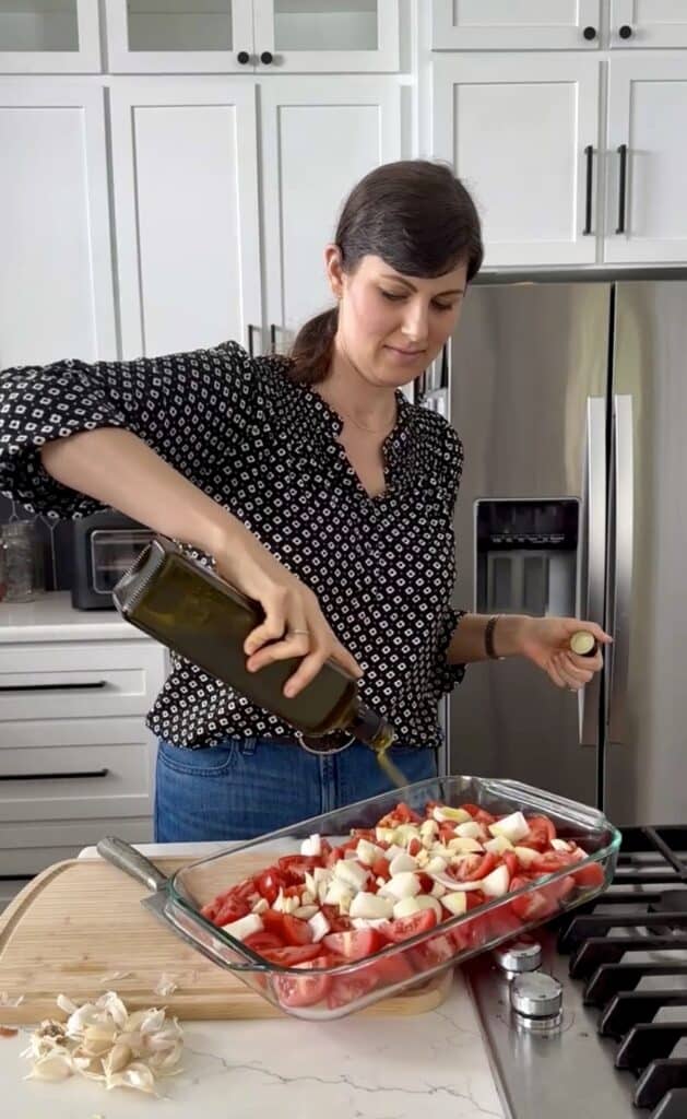 Aimee from Homemaker on a Budget drizzles olive oil on Roma tomatoes as she prepares to bake for making marinara sauce.