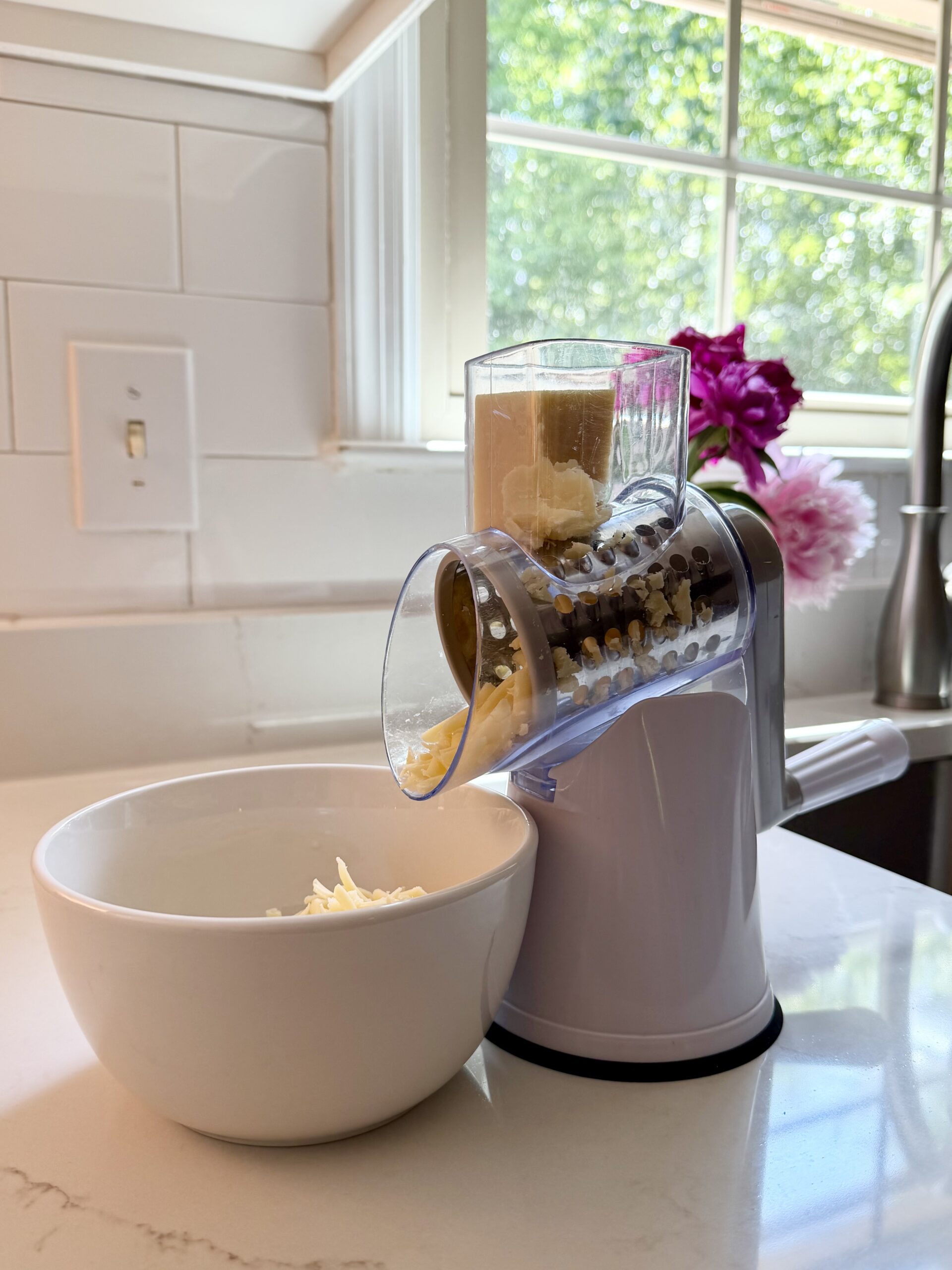 Aimee from Homemaker on a Budget uses a stainless steel rotary cheese grater to prepare savory muffins from pancake mix. 