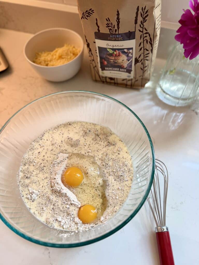 Aimee from Homemaker on a Budget sets up batter to make savory 5-ingredient meat and cheese muffins from pancake mix.