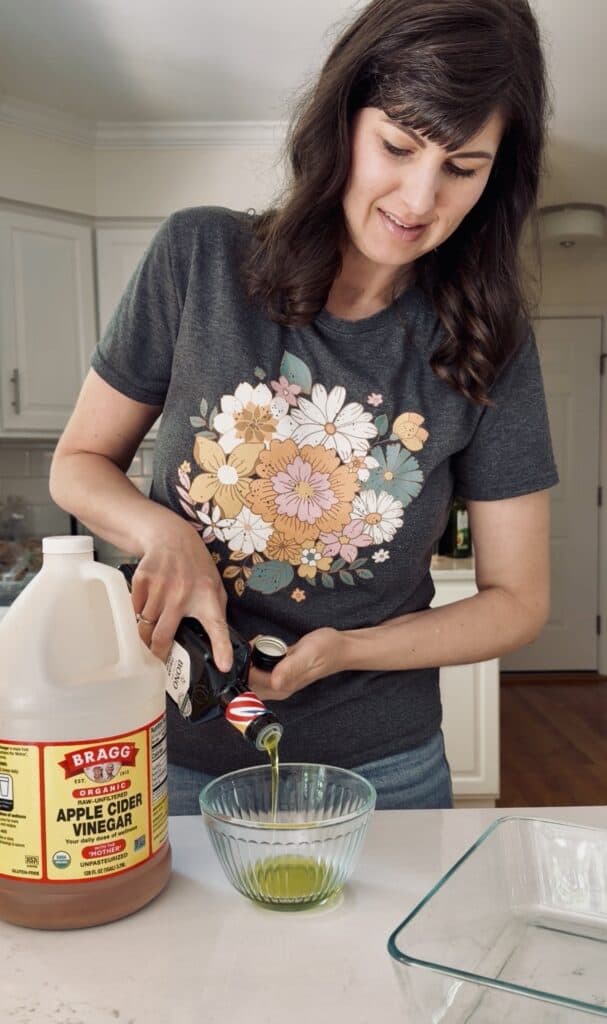 Aimee from Homemaker on a Budget whisks olive oil, apple cider vinegar, and garlic and herb seasoning together for chicken marinade. 