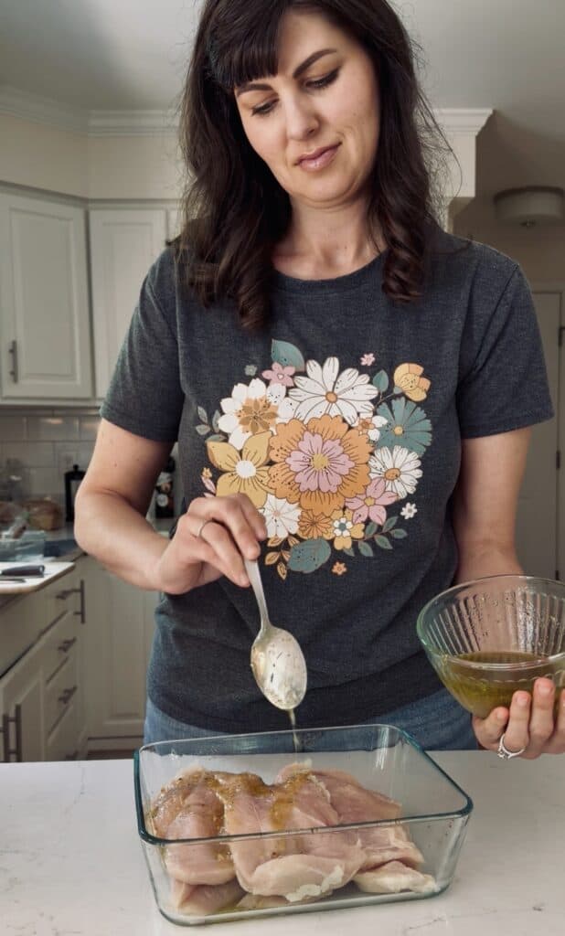 Aimee from Homemaker on a Budget pours apple cider marinade on chicken. 