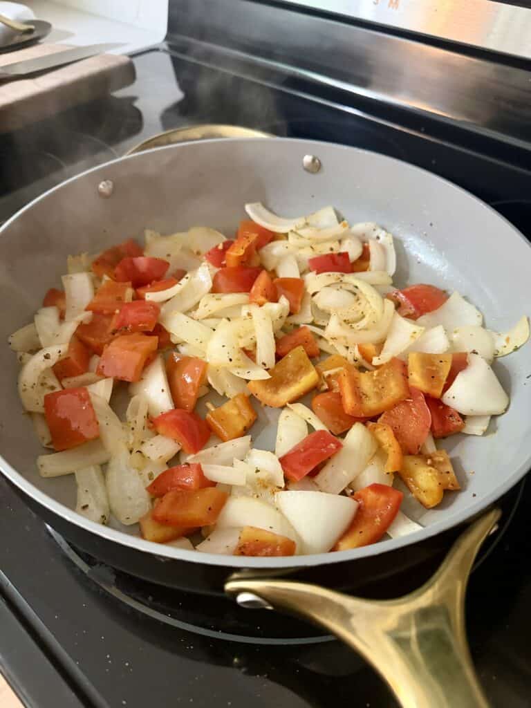 Aimee from Homemaker on a Budget cooks peppers and onions in olive oil for Hawaiian Chicken Bake. 