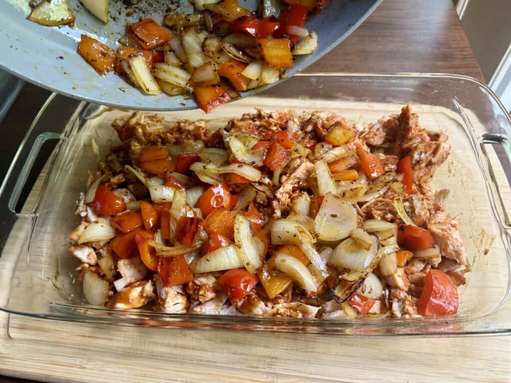 Aimee from Homemaker on a Budget spreads peppers and onions over casserole base in Hawaiian Chicken Bake. 