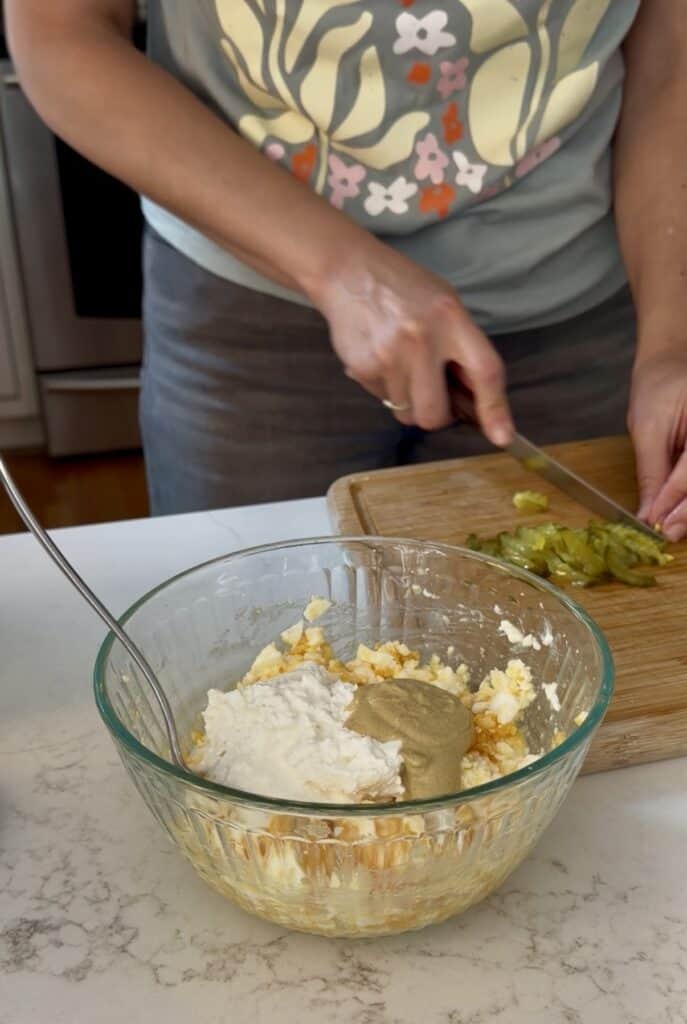 Adding diced dill pickles, cottage cheese, and curry powder, Aimee from Homemaker on a Budget completes her recipe for curried egg salad.