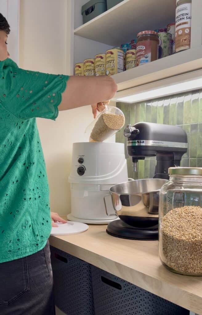 Grinding her wheat berries, Aimee from Homemaker on a Budget prepares to make fresh-milled wheat bread in a bread machine. 