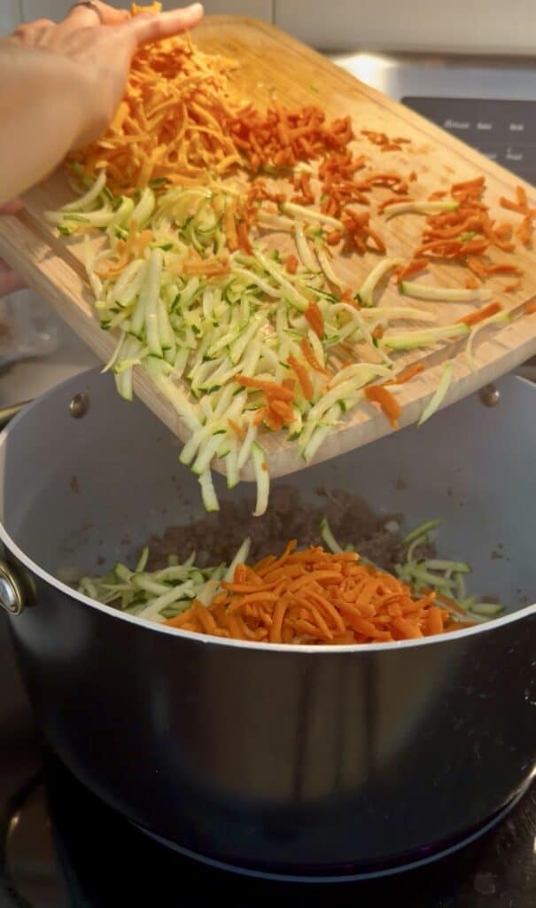 Aimee from Homemaker on a Budget can be seen adding in shredded vegetables to ground beef for creamy sweet potato hamburger soup. 