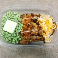 BBQ chicken slices, baked potato with garlic salt, butter, and cheese, and frozen peas with salt and butter